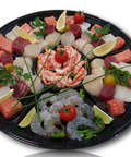 Assortiment frais pour fondue de poissons avec saumon, thon, crevettes, noix de Saint-Jacques et citron sur plateau noir.