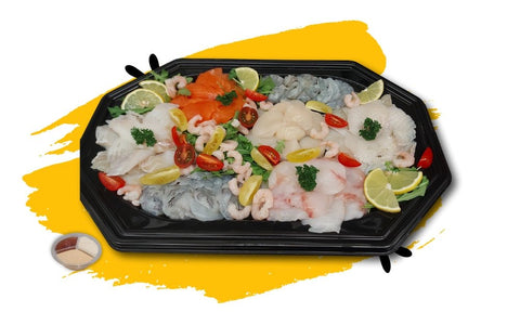 Plancha de poissons with fresh salmon, cod, monkfish, red tuna, scallops, haddock, northern bass, peeled shrimp, garnished with lemon slices and cherry tomatoes on a black platter