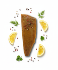 Truite fumée Suisse poivre au citron avec tranches de citron, herbes fraîches et grains de poivre colorés.