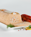 Terrine de poissons artisanale avec morceaux de crustacés, accompagnée d'un homard, citron et herbes fines sur plat blanc