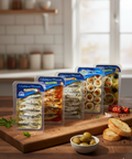 Assortment of marinated anchovy fillets in oil with various flavors displayed on wooden board with bread and olives