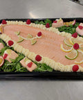 Saumon en Bellevue cooked salmon fillet with mayonnaise, lemon slices, raspberries, and greens on black tray