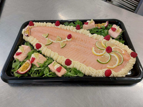 Saumon en Bellevue cooked salmon fillet with mayonnaise, lemon slices, raspberries, and greens on black tray