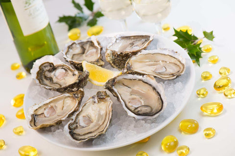 Assiette de huîtres fraîches sur lit de glace avec quartier de citron et bouteille de vin blanc en arrière-plan