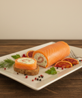 Roulade fait maison au saumon frais et fumé avec crème sans lactose, garnie d'aneth et tranches d'orange sanguine, servie sur pain sur assiette blanche.
