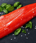Saumon fumé sauvage Sockeye entier avec herbes fraîches et sel sur plaque noire