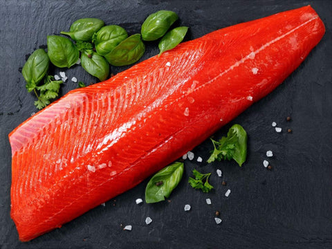 Saumon fumé sauvage Sockeye entier avec herbes fraîches et sel sur plaque noire